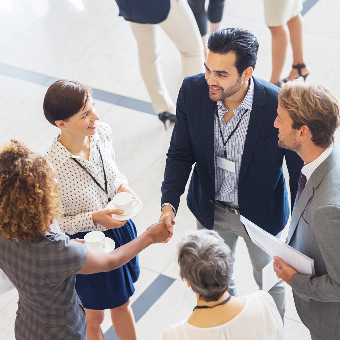 Community-i 5 people greeting eachother in a large room.