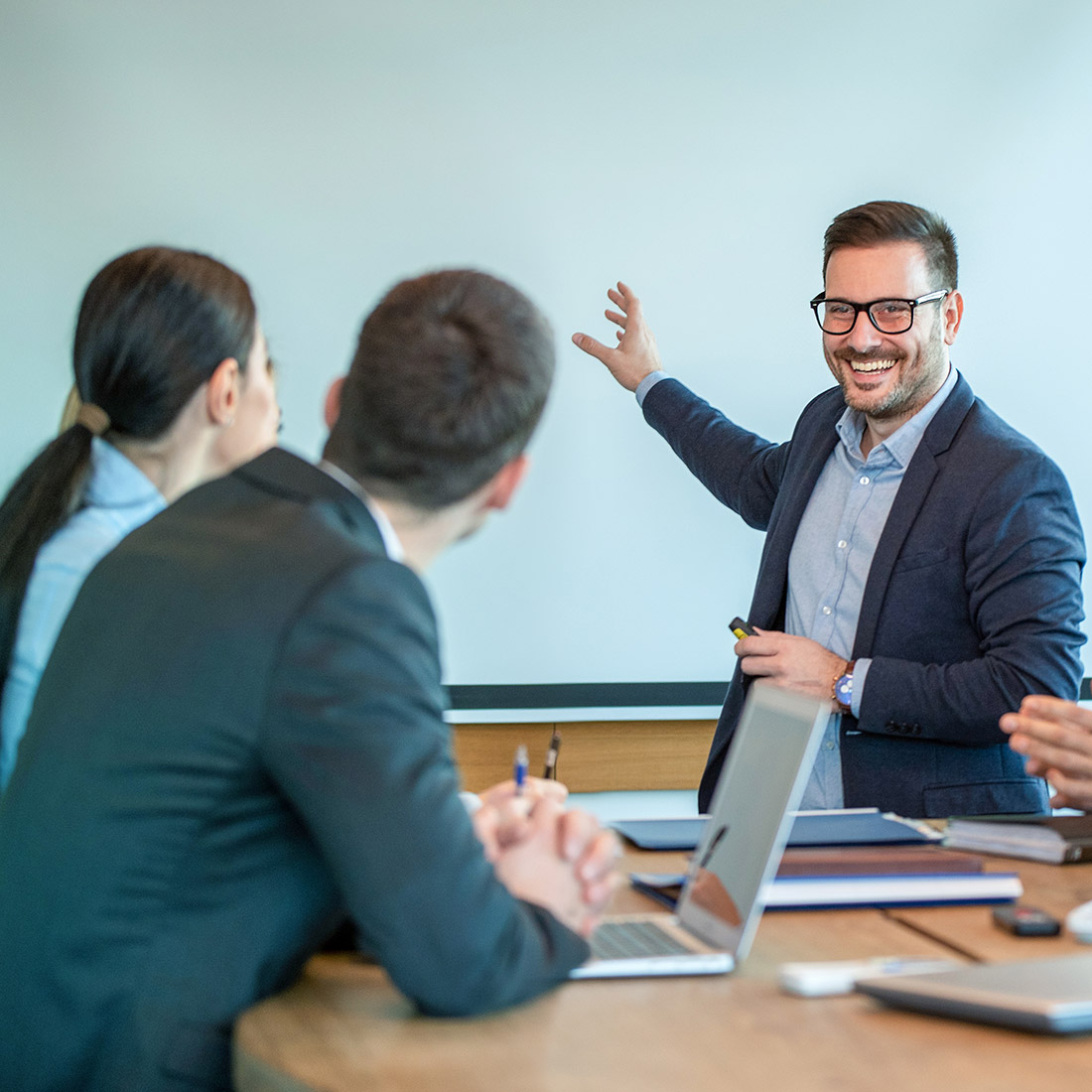 Consulting-i Three people at a table - one is instructing the other two.