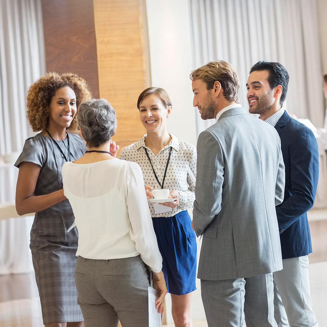 5 people greeting eachother in a large room.