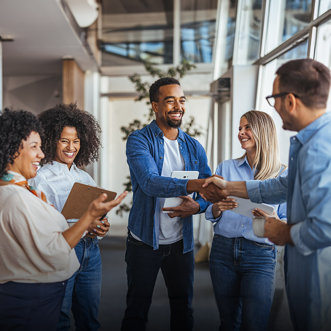 Business people standing in a group shaking hands and smiling
